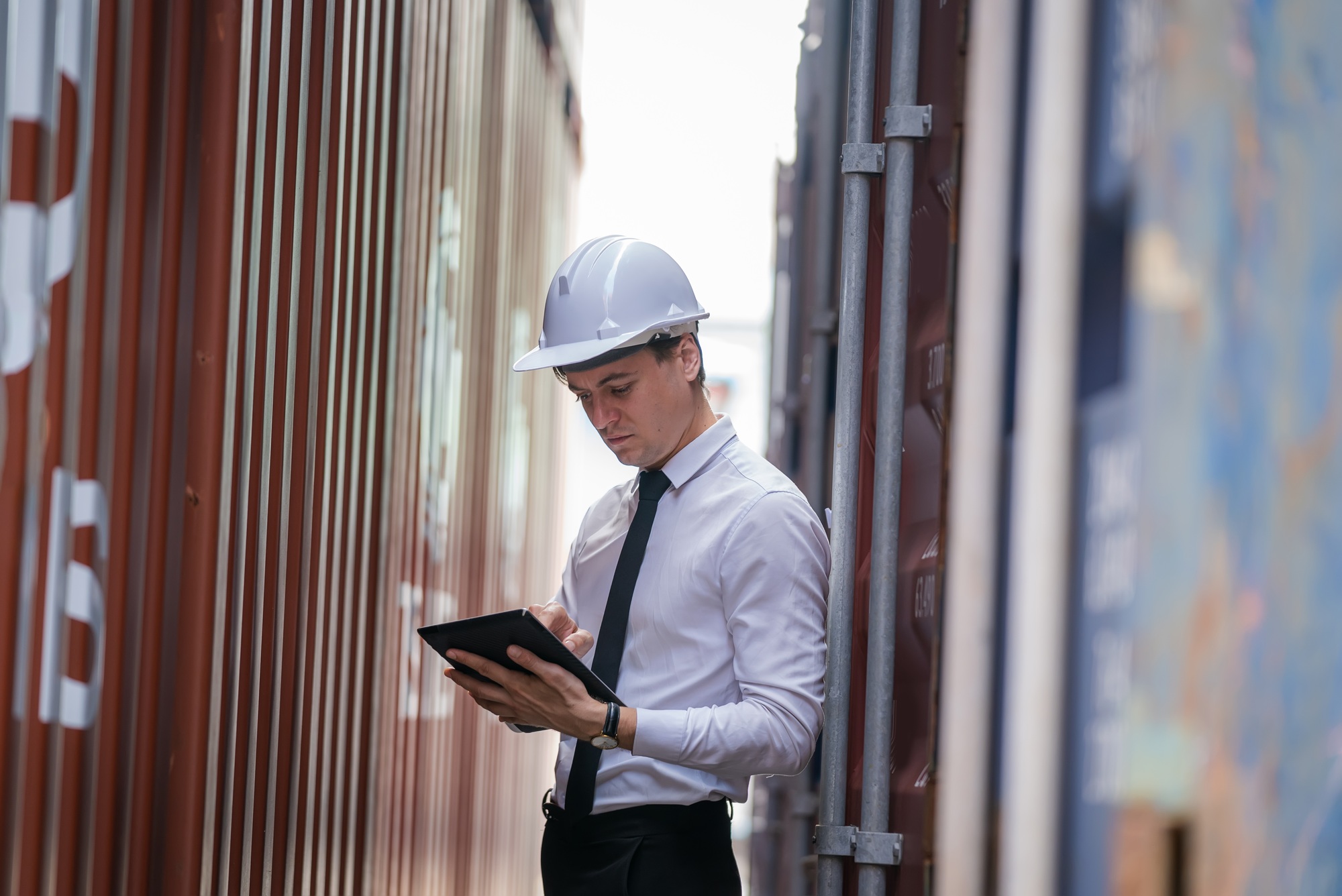 Businessman checking on shipping containers at container yard warehouse.
